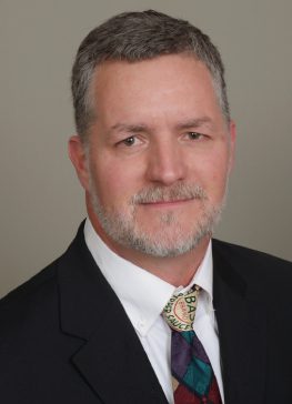 A man in suit and tie with white beard.